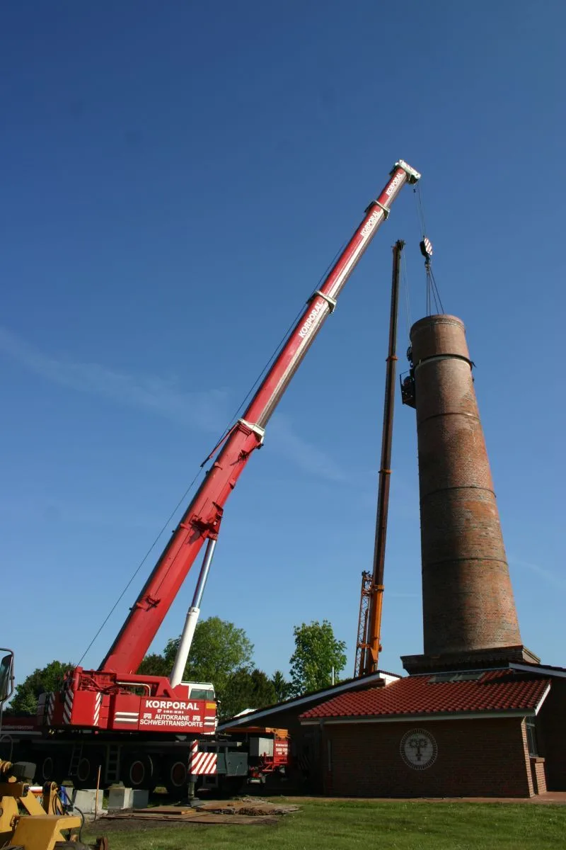 Korporal Kran hebt ein Schornsteinsegment vor blauem Himmel